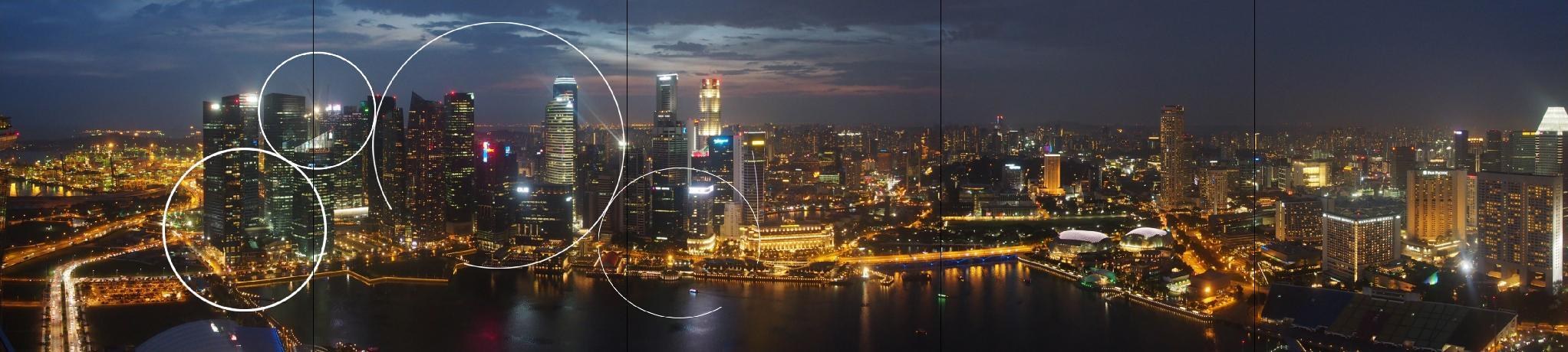 Storyboard frame: a wide night time city skyline filling the ten screen wall, with four thin white circle outlines of different sizes drawn onto the left, no content inside them yet
