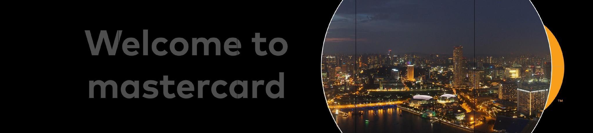 Storyboard frame: the Welcome to mastercard copy fading out while the left circle of the mark has become a circular photograph of a lit city skyline at night, expanding across the black wall
